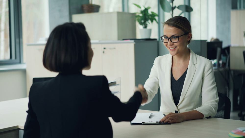 A professional greeting a client in a bright office