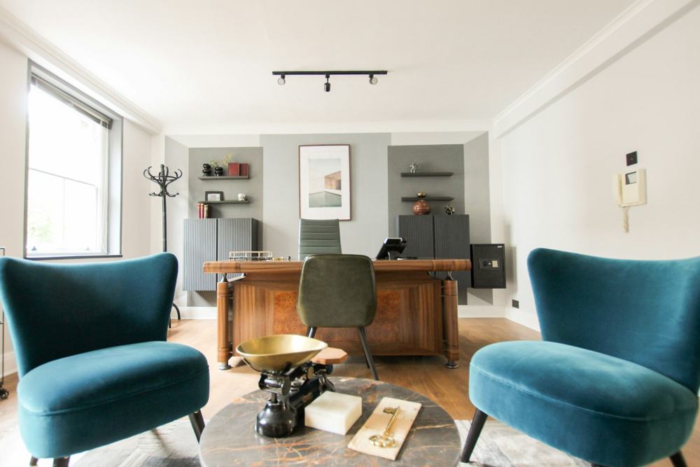 A bright office with a desk and armchairs
