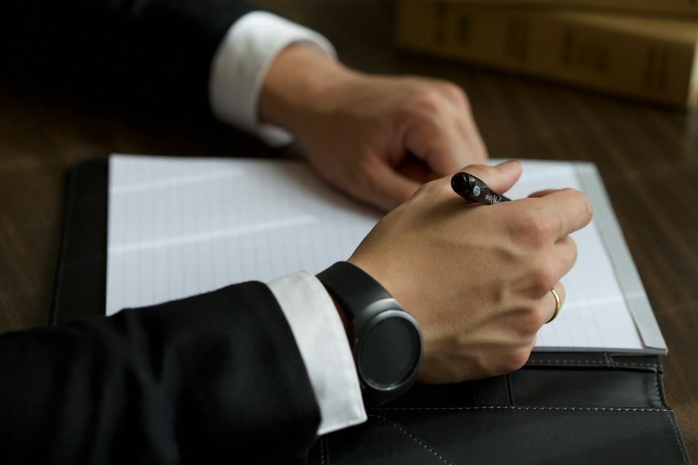 A person signing a document with a pen